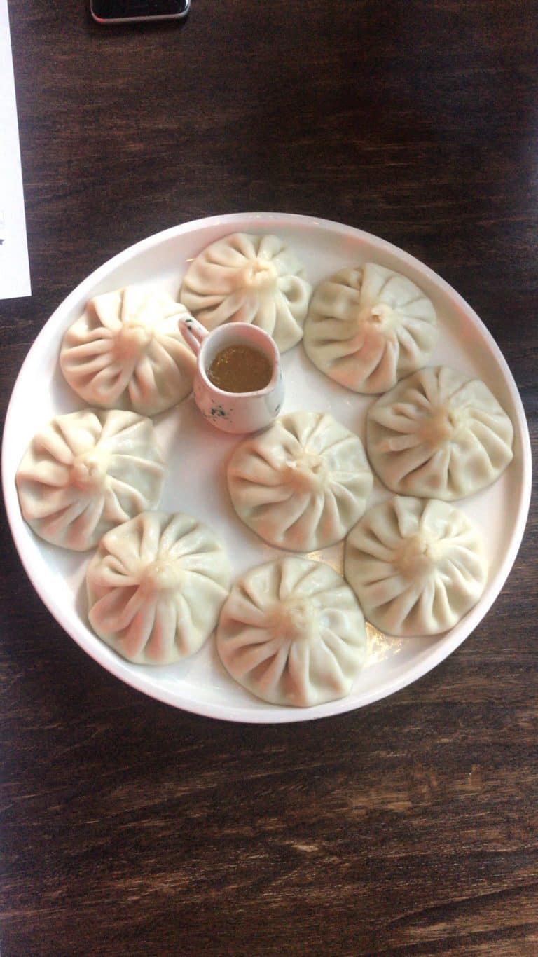 A weekend guide to Georgia showcasing a white plate topped with dumplings and a cup of coffee.