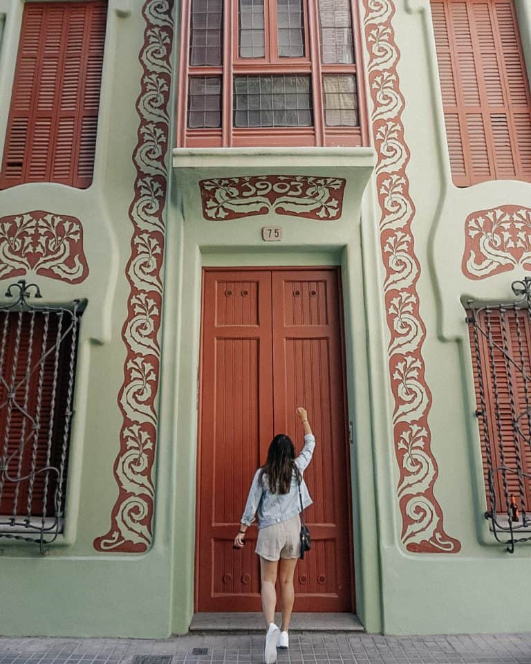 A woman standing in front of a red door in Barcelona, Spain.