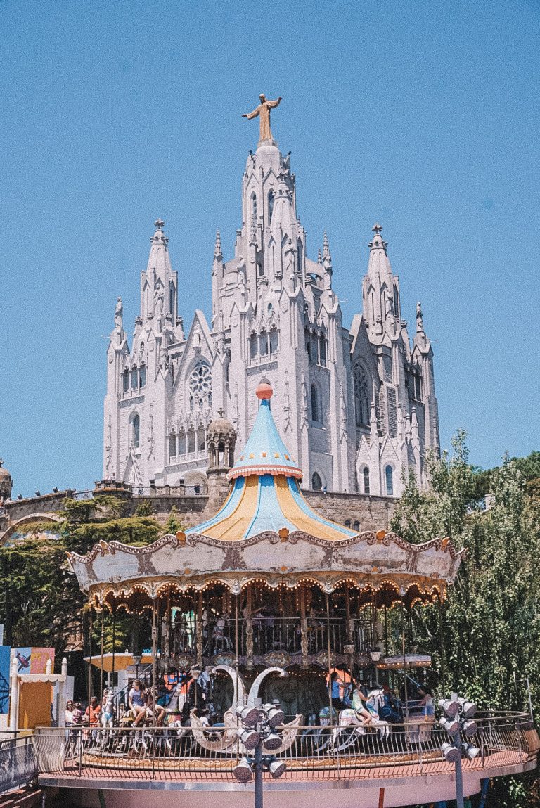 A carousel in front of a large building in Barcelona, Spain.
