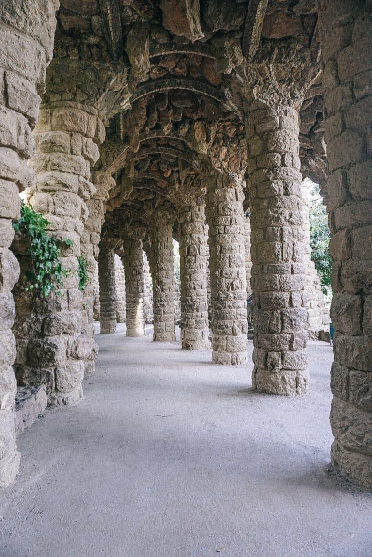A walkway lined with stone pillars and plants in Barcelona, Spain.
