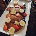 a white plate topped with pancakes covered in fruit.