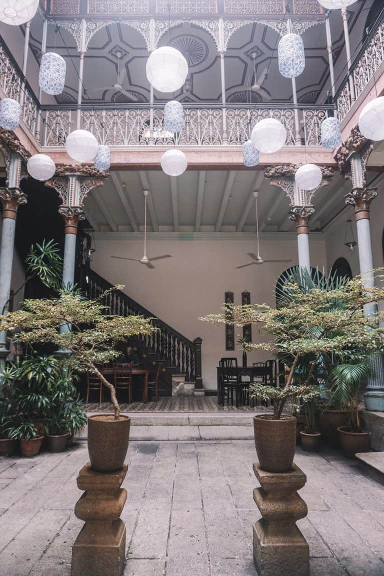 A charming courtyard decorated with potted plants and hanging lanterns in Penang, Malaysia.
