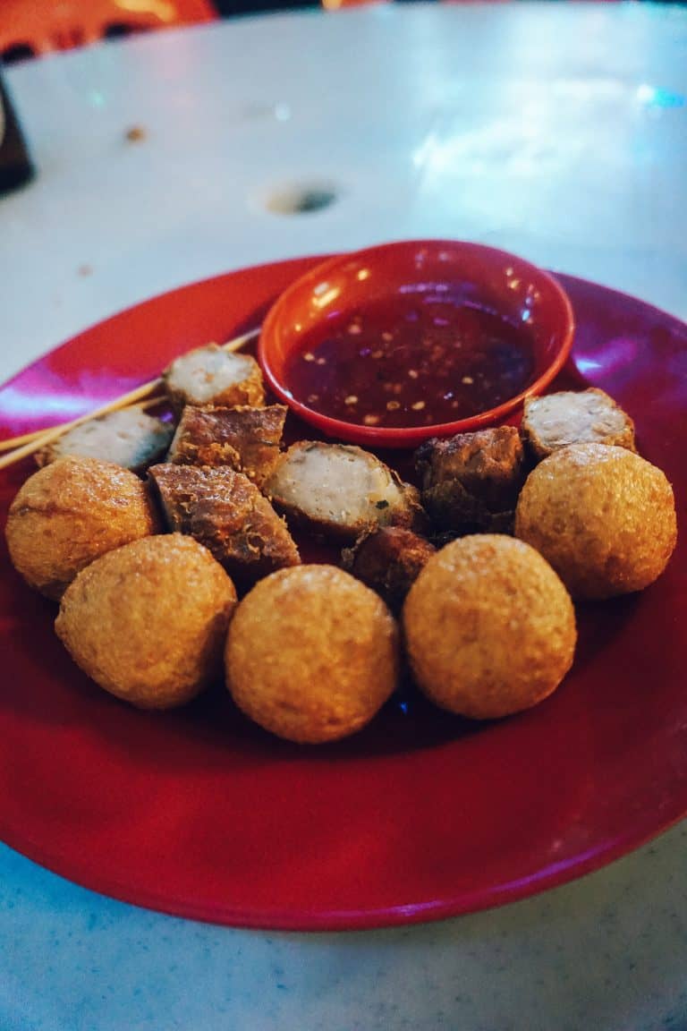 A red plate topped with meatballs and dipping sauce from Penang, Malaysia.