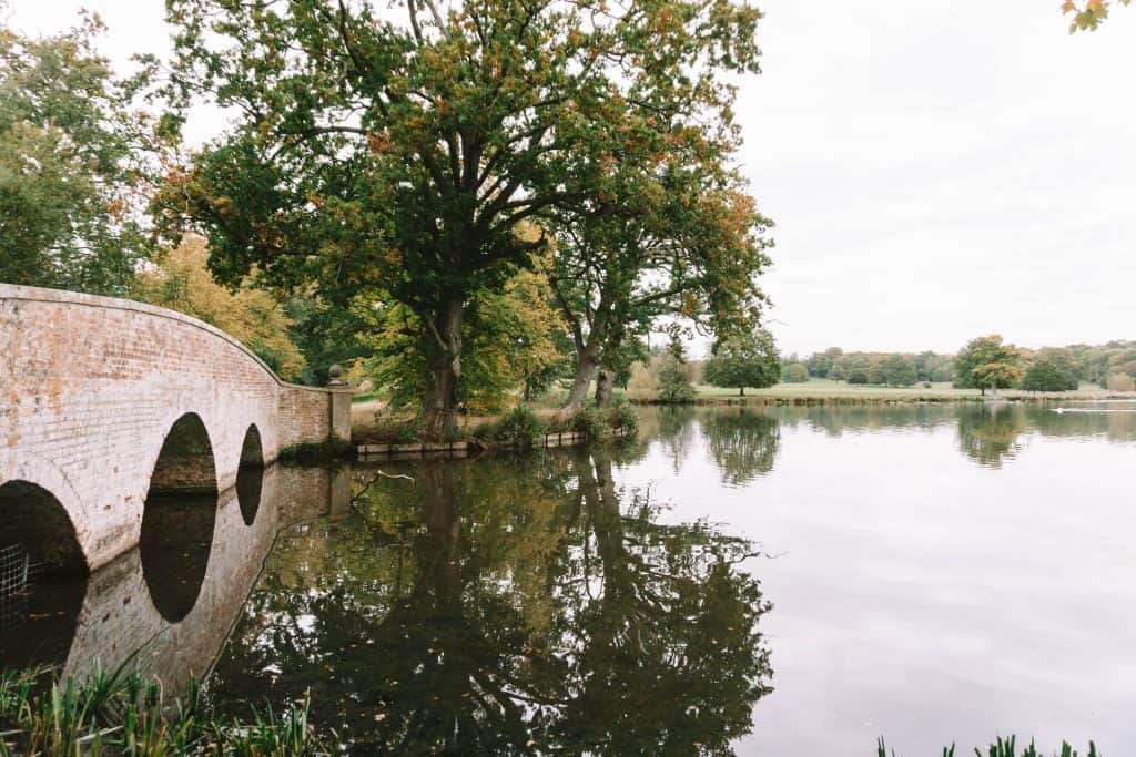 A stone bridge crossing the water in the English countryside.