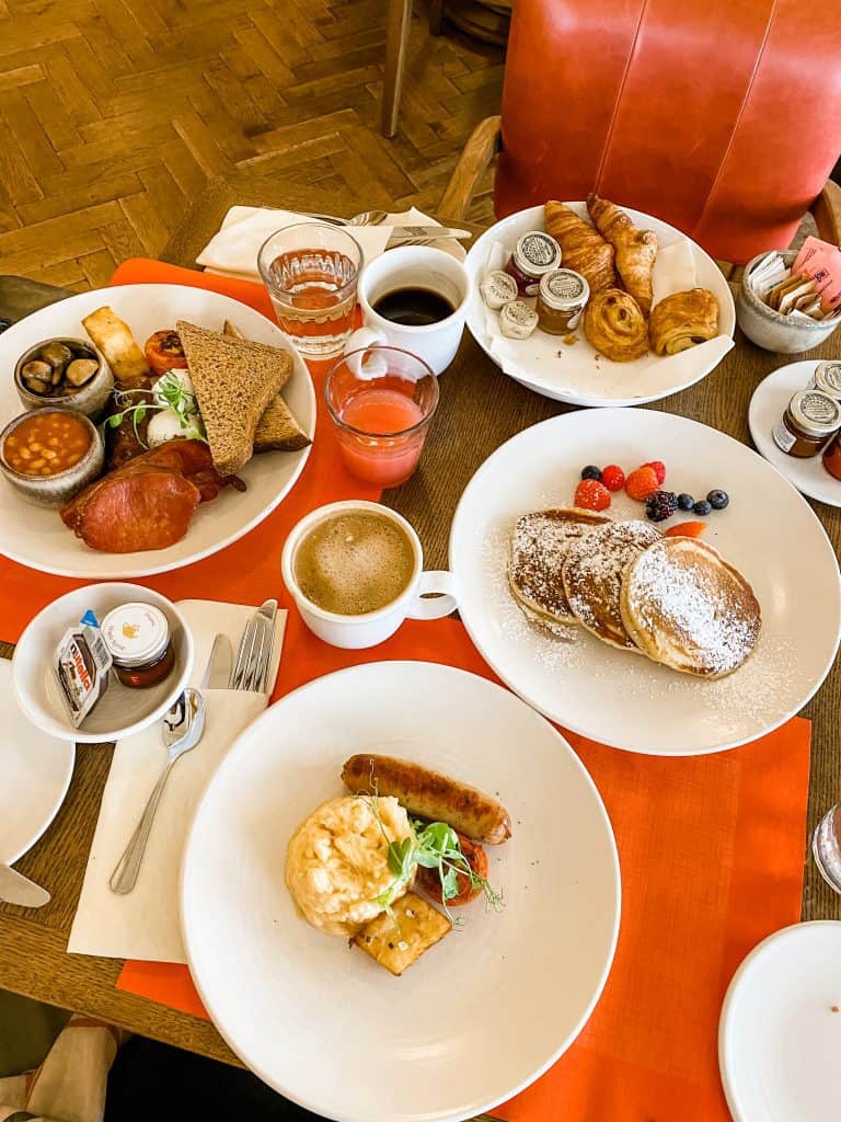 A table adorned with plates of savory cuisine and refreshing beverages at a luxury hotel in the English countryside.