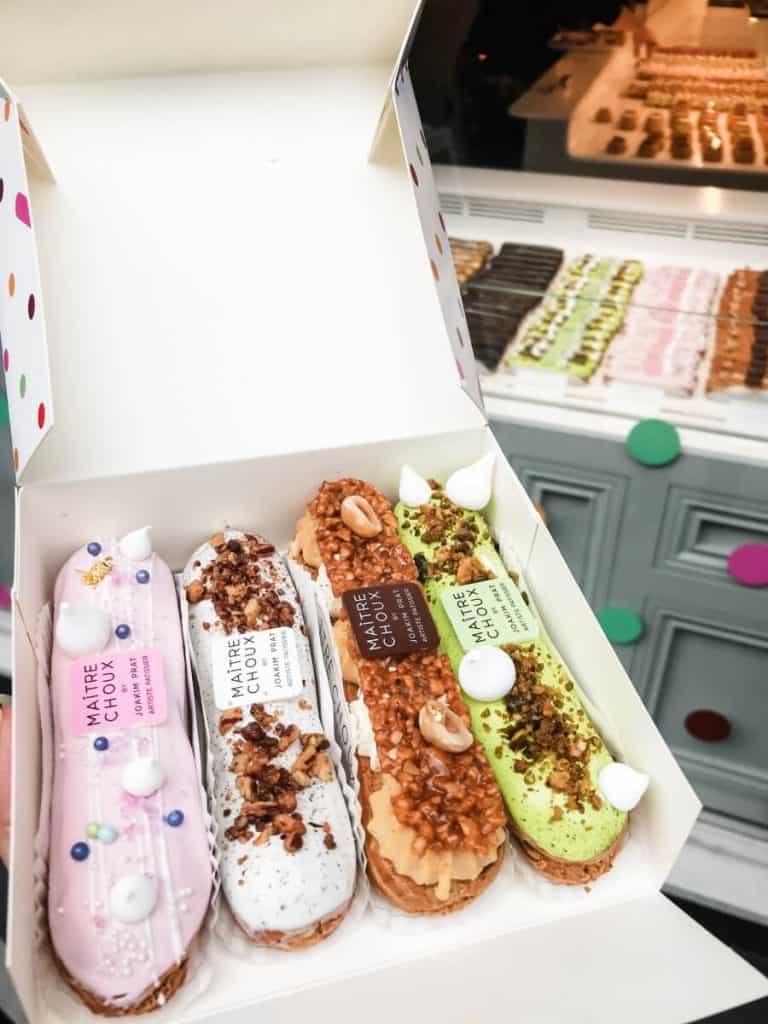 a person holding a box of donuts in it from a takeaway bakery where tipping would not be required in london