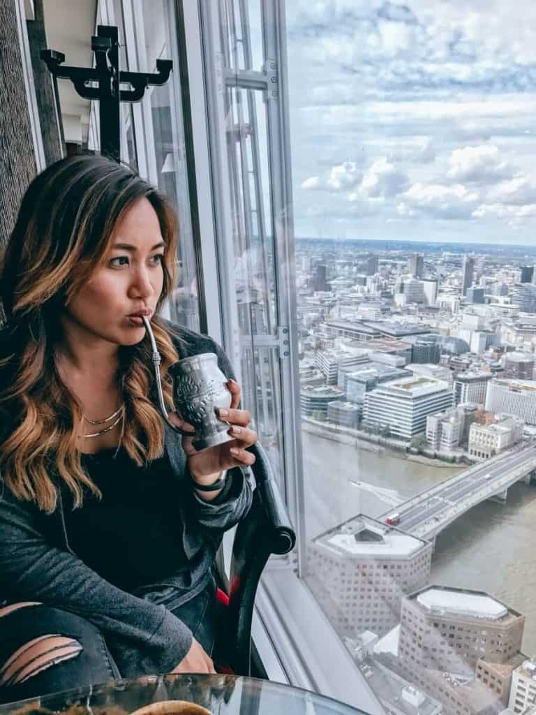 a woman drinking a drink in a high rise restaurant.