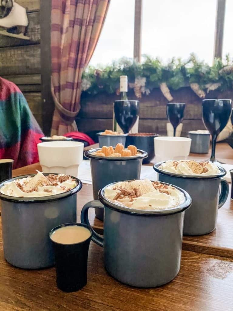 a wooden table topped with cups filled with food.