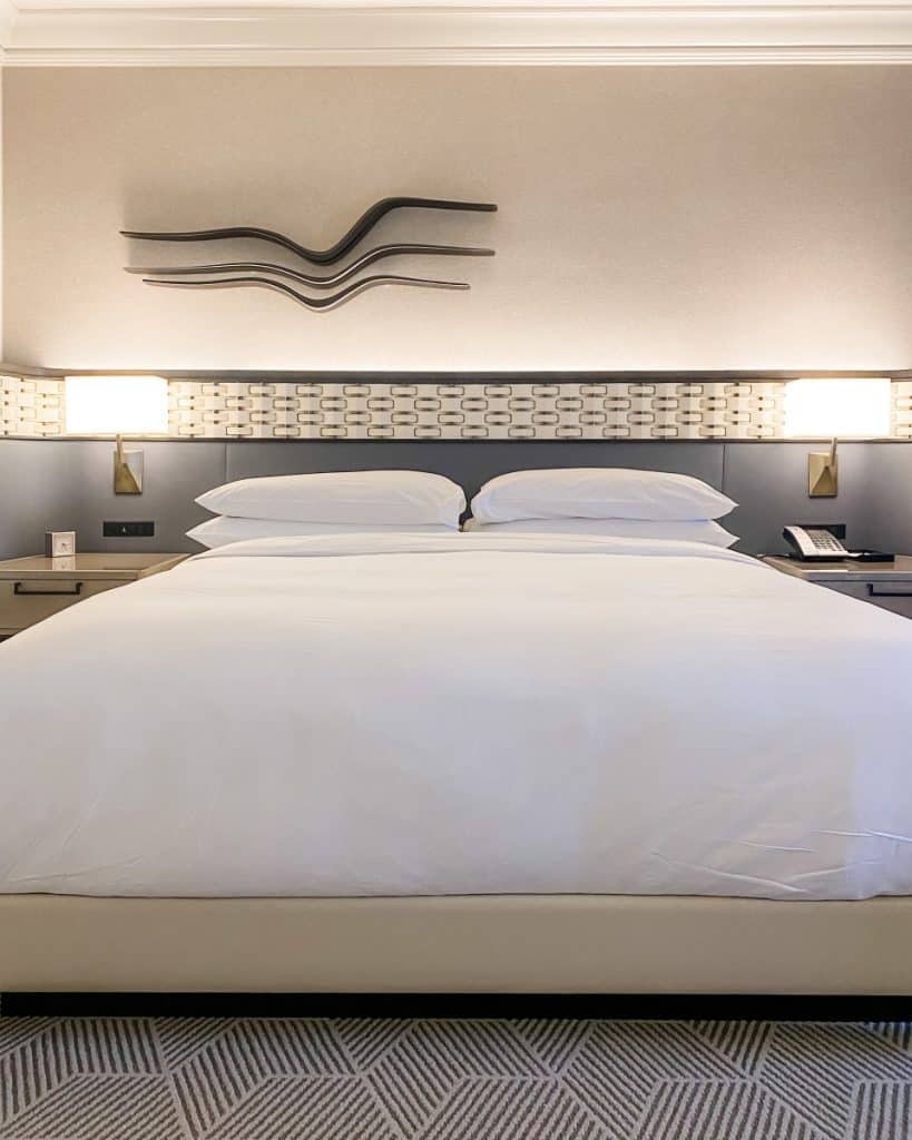 A Hotel Review of Park Hyatt Aviara reveals a bed with a white comforter and pillows.