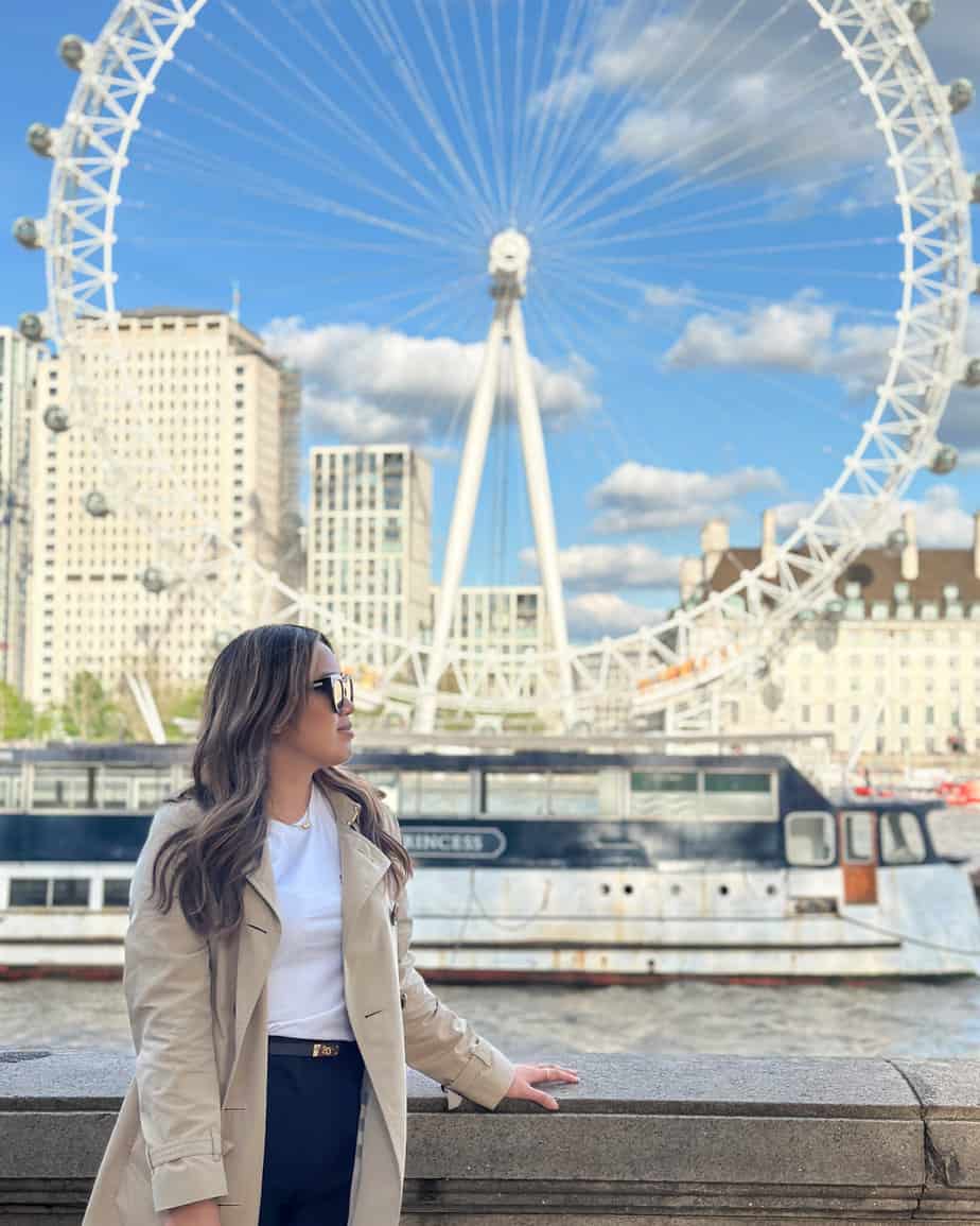 a woman leaning on a wall with a ferris wheel in the background.